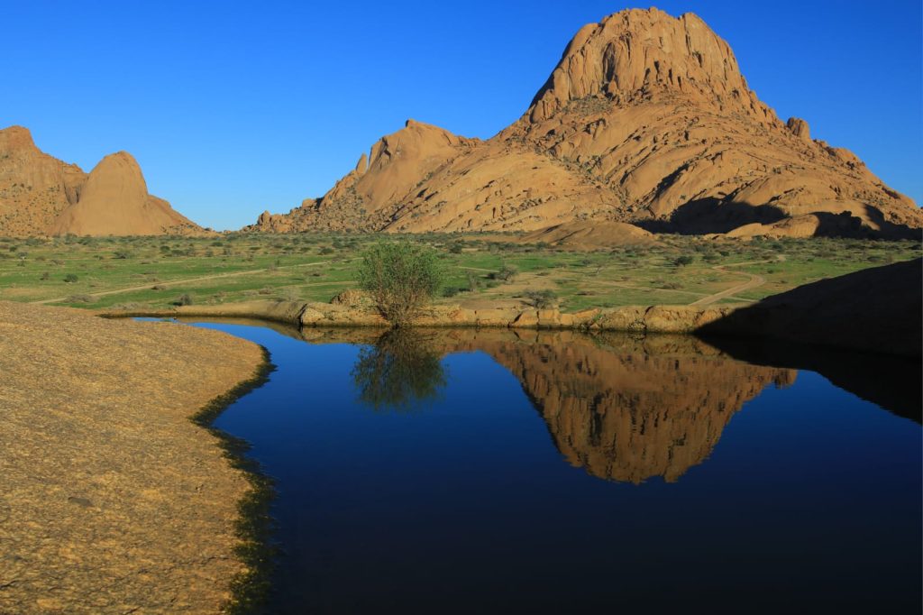 Spitzkoppe granite peaks reflected in a green season rock pool, Namibia